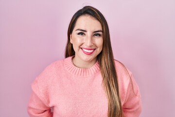 Fototapeta premium Young hispanic woman standing over pink background with a happy and cool smile on face. lucky person.