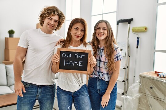 Mother And Couple Smiling Confident Holding Our First House Blackboard At Home