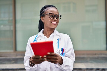 African american woman doctor smiling confident using touchpad at hospital