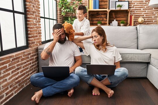 Family using laptop and kid bothering their parents at home