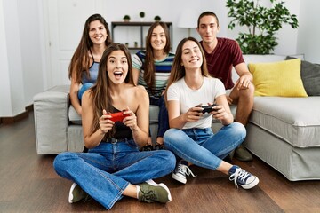 Group of young friends smiling happy playing video game at home.