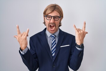 Caucasian man with mustache wearing business clothes shouting with crazy expression doing rock symbol with hands up. music star. heavy music concept.