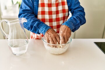 Senior man cooking dough at kitchen