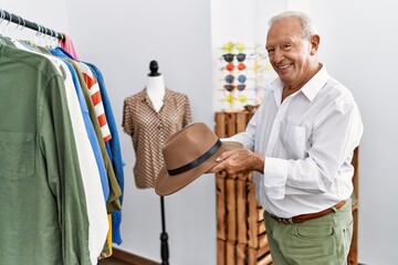 Senior man customer holding hat at clothing store
