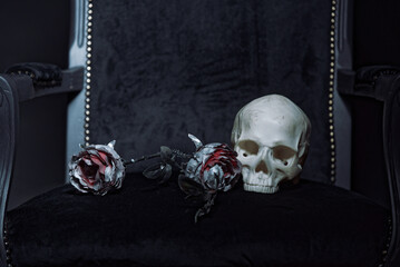 An old skull next to dead, silver rose flower, dark and horror halloween image