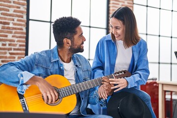 Man and woman musicians having classical guitar lesson at music studio