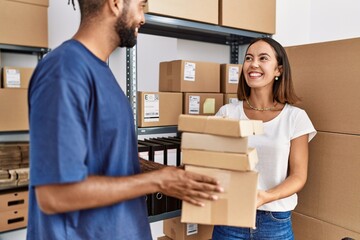 Man and woman business partners smiling confident holding packages at storehouse