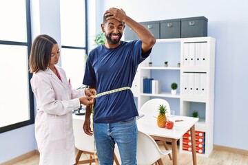 Dietitian at the clinic using tape measure measuring waist of client stressed and frustrated with...