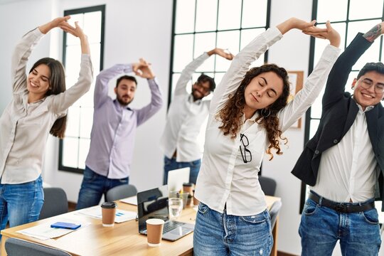 Group of business workers stretching arms in relax time standing at the office.