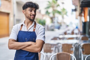 Young arab man waiter standing with arms crossed gesture at restaurant