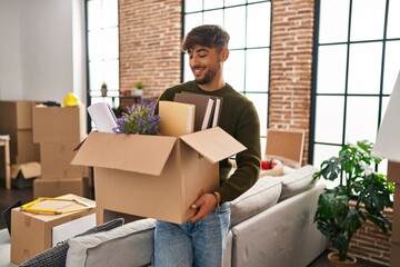 Young arab man smiling confident holding package at new home