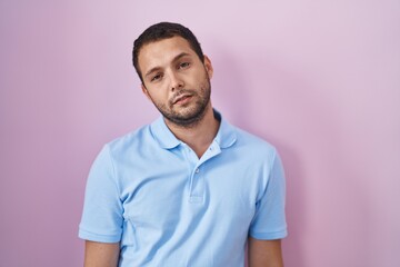 Obraz premium Hispanic man standing over pink background looking sleepy and tired, exhausted for fatigue and hangover, lazy eyes in the morning.