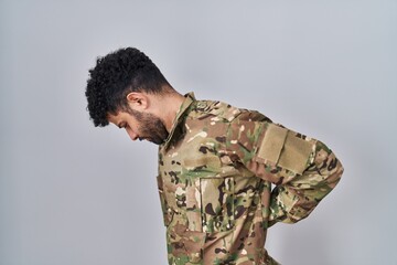 Arab man wearing camouflage army uniform suffering of backache, touching back with hand, muscular...