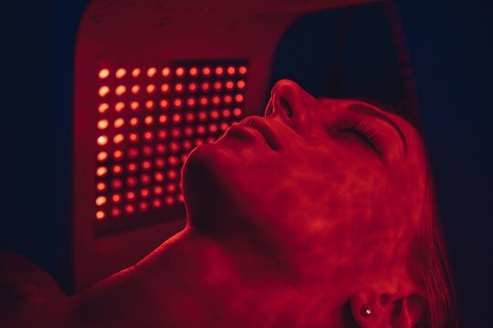 LED red light is treating the facial skin of a young woman.