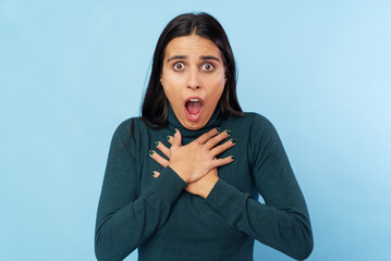 Young shocked woman against studio blue background