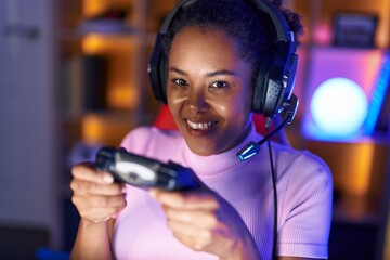 African american woman streamer playing video game using joystick at gaming room