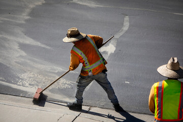 Obraz premium A worker in a safety vest sweeping a gutter