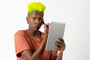 A gay black man putting on makeup, LGTBI concept, correcting blemishes with a mirror