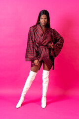 Black ethnic man in a studio, LGTBI concept, portrait wearing a red kimono and white high heels