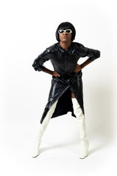Black ethnic man in studio with white background, LGTBI concept, wearing leather skirt and white heels