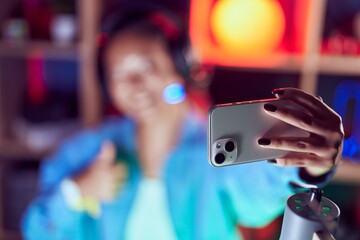 Young chinese woman streamer smiling confident make selfie by smartphone at gaming room