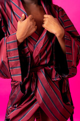 Black ethnic man in a studio, LGTBI concept, red kimono on a pink background