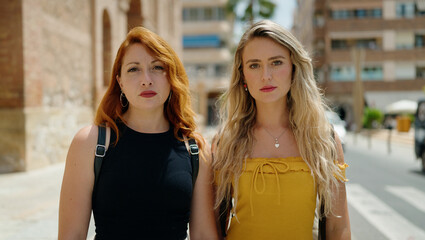 Two women standing together with relaxed expression at street