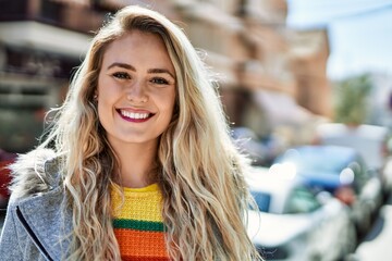 Young blonde woman smiling at the city