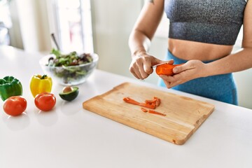 Young woman cutting carrot for salad at kitchen