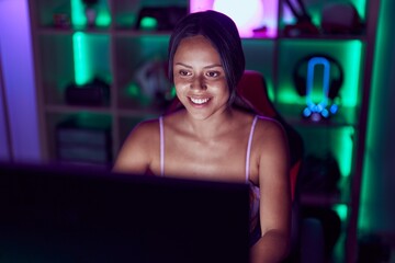 Fototapeta na wymiar Young hispanic woman streamer smiling confident using computer at gaming room