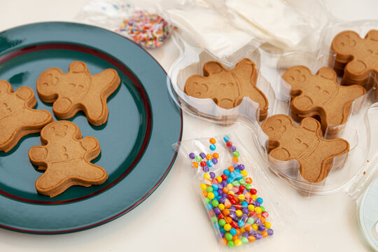 Gingerbread men on a green plate. Ingredients for decorating cookies. Developing activities with children for Christmas