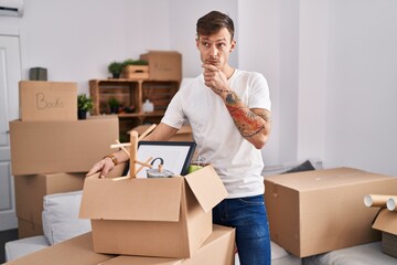 Caucasian man holding screwdriver at new home serious face thinking about question with hand on chin, thoughtful about confusing idea