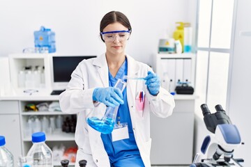 Young hispanic woman wearing scientist uniform holding test tube at laboratory