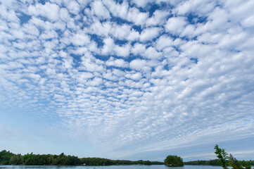 Fluffy white clouds over a lake in Ontario on a blue sky background.