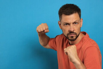 Naklejka premium Man ready to fight on light blue background, space for text