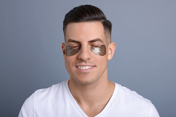 Man with dark under eye patches on grey  background