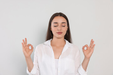 Find zen. Beautiful young woman meditating on white background