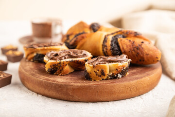 Homemade sweet bun with chocolate cream and cup of coffee on a gray. side view, selective focus.