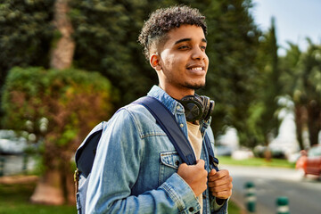 Hispanic young man smiling wearing headphones at the university campus