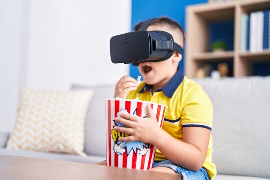Adorable hispanic boy watching 3d movie sititng on sofa at home