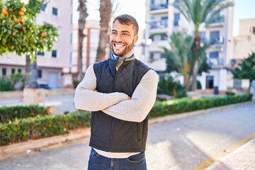 Young hispanic man smiling confident standing with arms crossed gesture at park