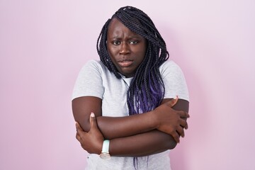 Young african woman standing over pink background shaking and freezing for winter cold with sad and shock expression on face