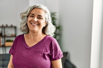 Middle age grey-haired woman smiling happy standing at home.