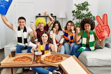 Group of young people wearing team scarf cheering football game annoyed and frustrated shouting with anger, yelling crazy with anger and hand raised