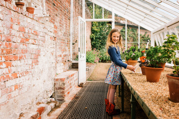 girl smiling stood looking at plants in a green house in the garden