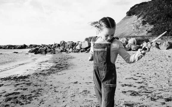 black and white picture of girl playing bat and ball at the beach