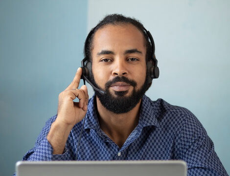 Portrait of a latin man telesales worker working wear 
headset contacting customers to inform them about service,
 answer questions about products. Call center operator agent,
 clients support conce