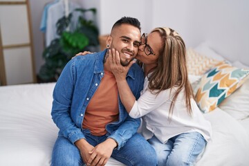 Man and woman mother and son sitting on bed kissing at bedroom