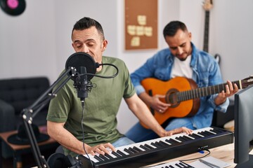 Fototapeta na wymiar Two men musicians singing song playing piano and classical guitar at music studio