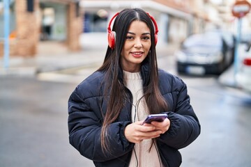 Young beautiful hispanic woman smiling confident listening to music at street